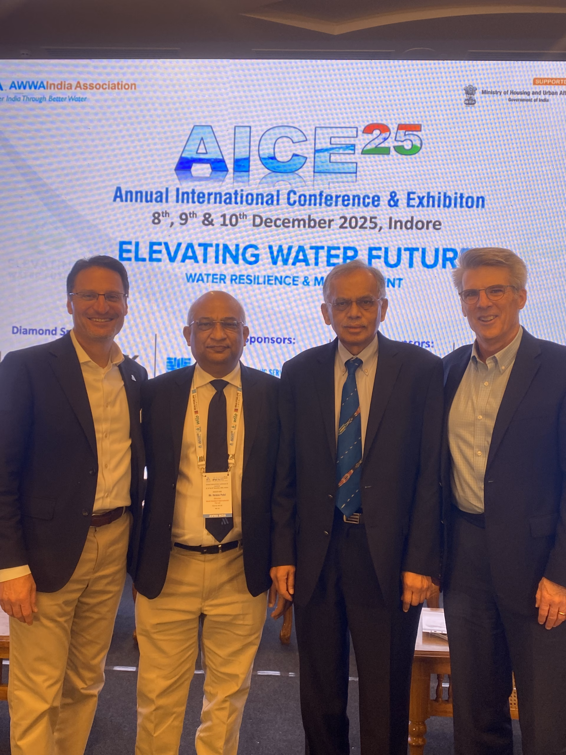 Four men stand on stage for a photo at a conference.