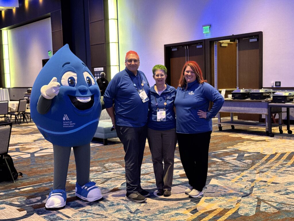 Three people pose with a mascot as part of a fundraiser.
