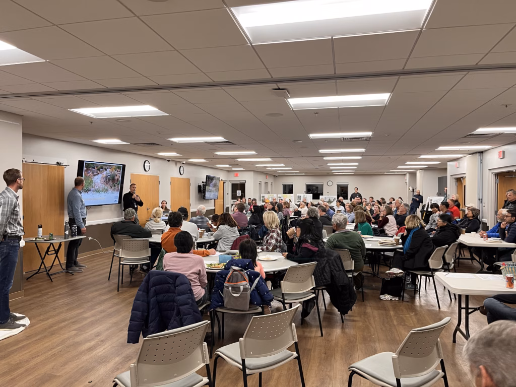 A room filled with adults watching a presentation.