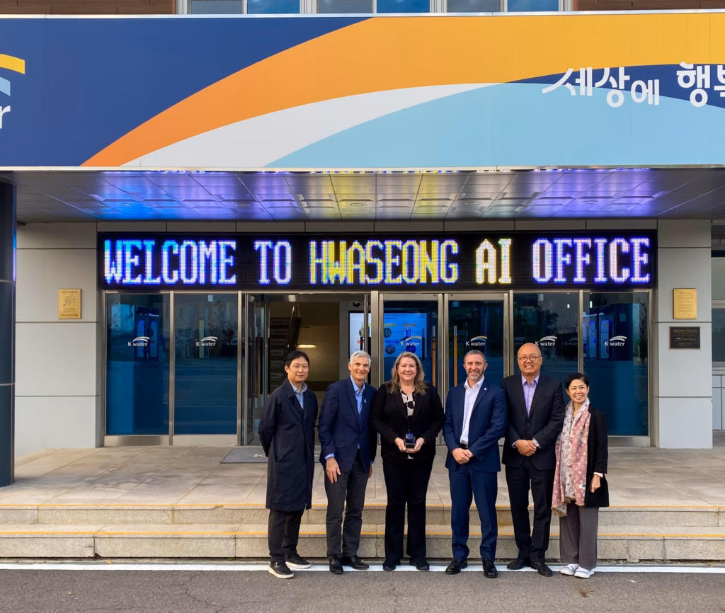 A group of five adults pose for a picture outside of a water treatment plant.
