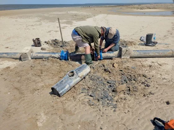 Two men repair a damaged water pipe.