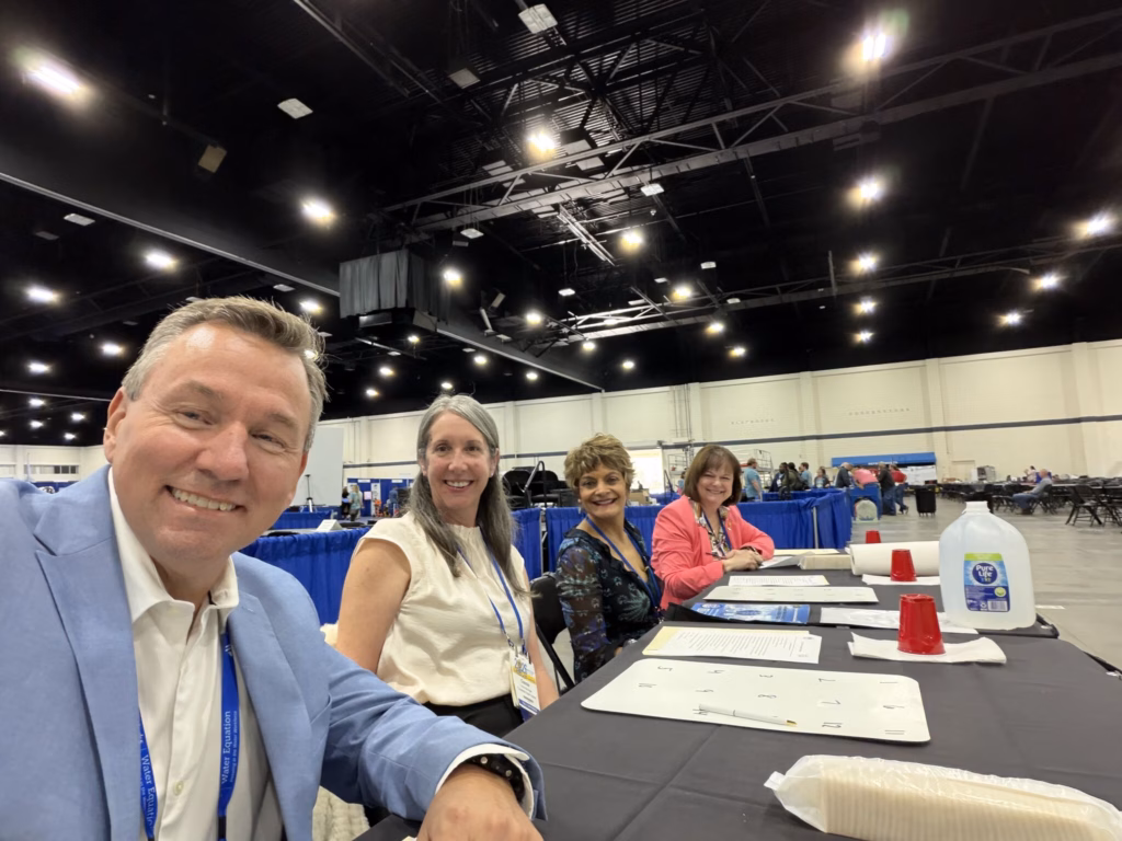 Four adults seated at a table pose for a selfie.