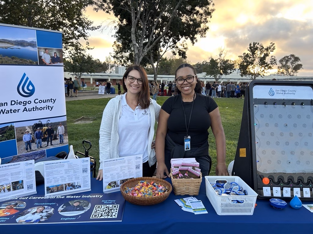 Two adults pose in front of a table at a career fair.