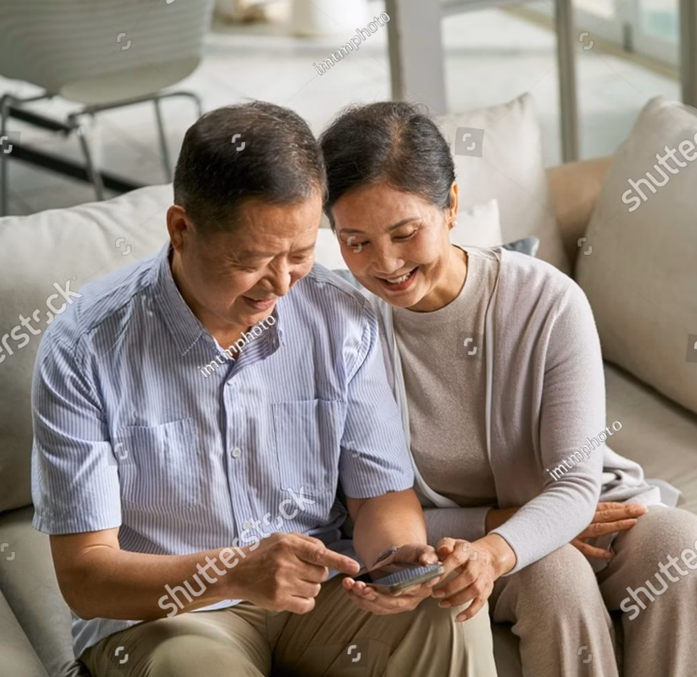 stock-photo-happy-senior-asian-couple-sitting-on-couch-at-home-using-cellphone-together-2460745435
